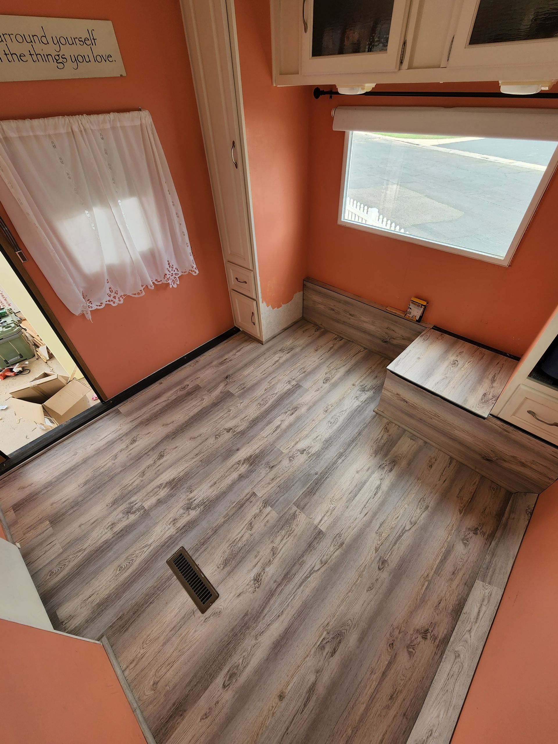 Interior of a small room with wood-look flooring, peach walls, and a window.