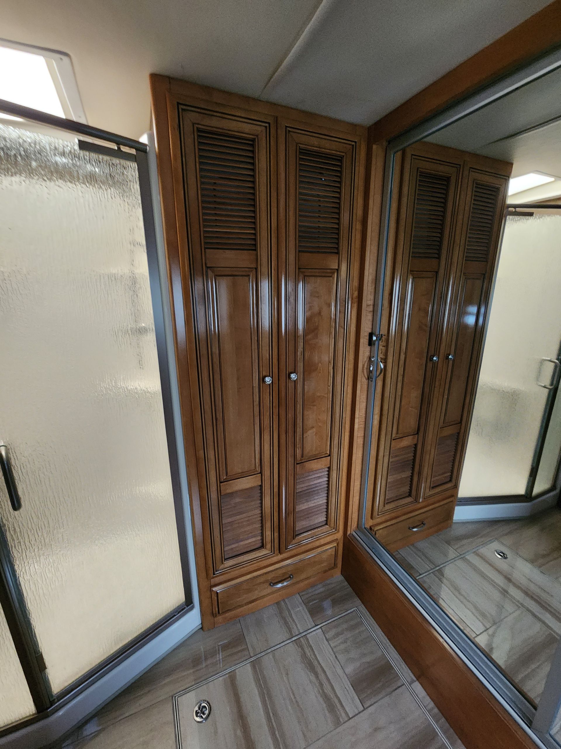 Wooden wardrobe in a room with a shower and a bed.