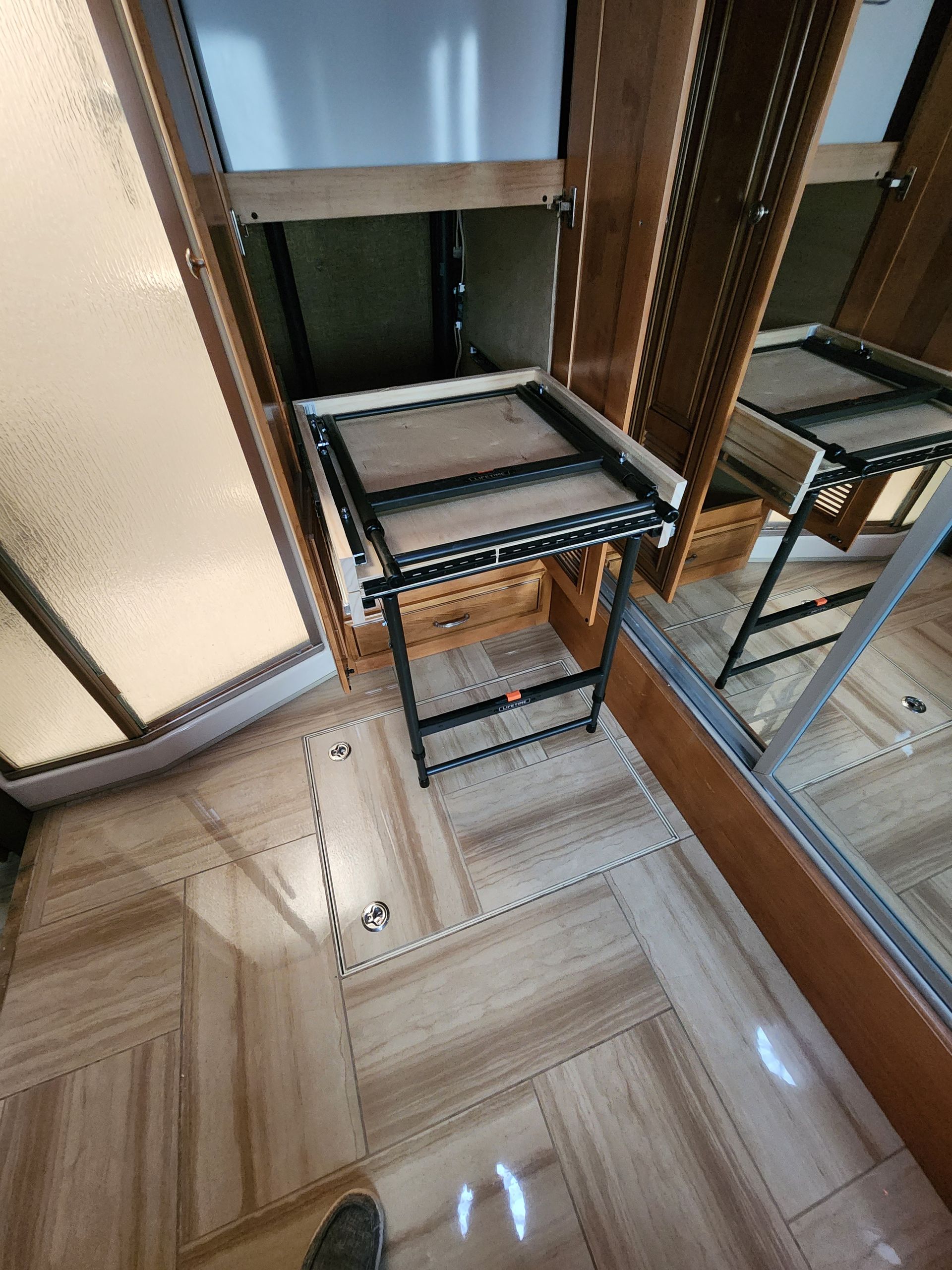 Closet with a pull-out shelf, wooden doors, and tiled floor.