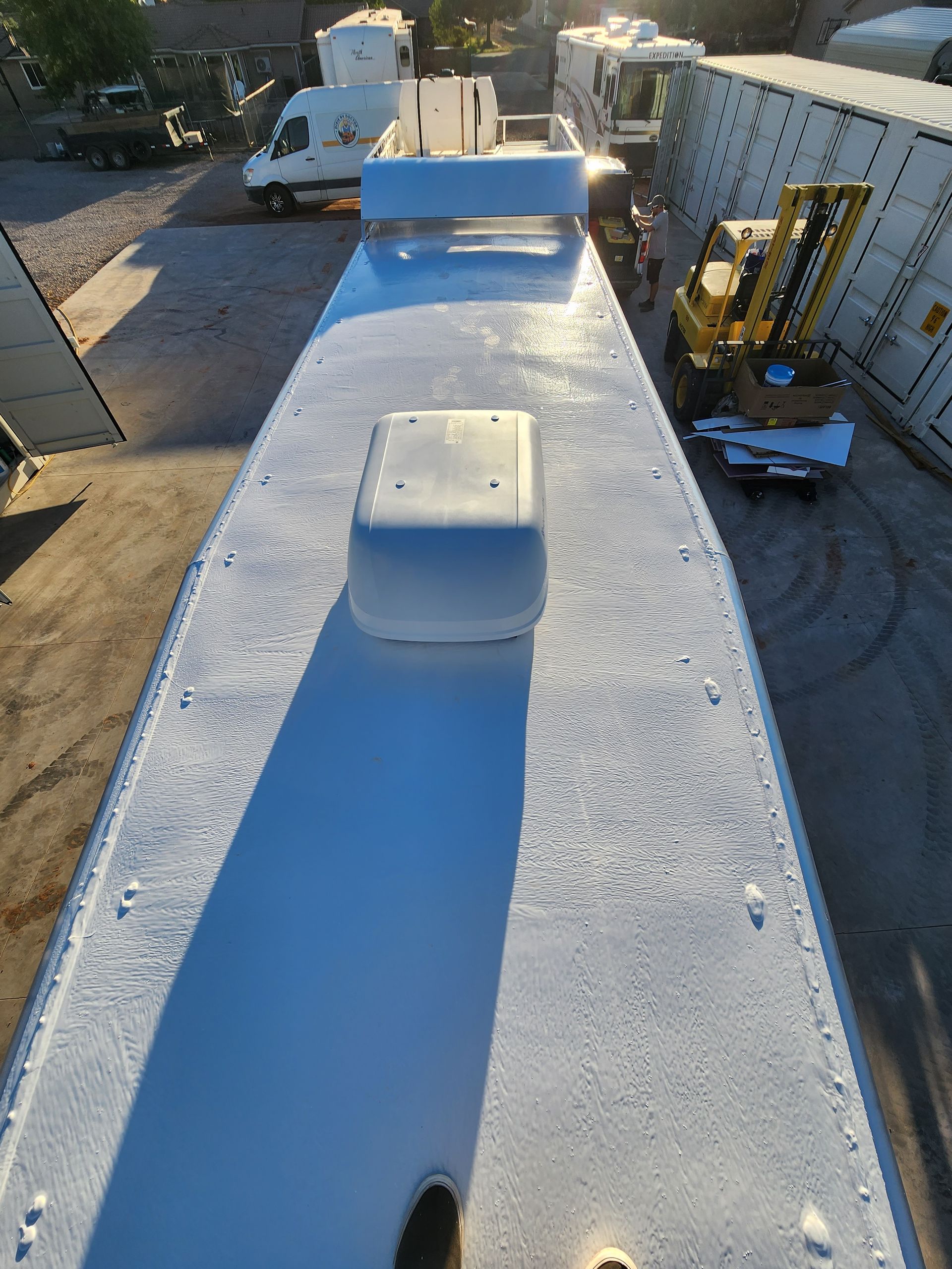Overhead view of a white vehicle roof with a white domed structure and a long shadow.