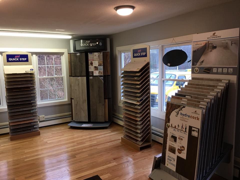 Flooring showroom with various sample displays on hardwood floors, near windows.