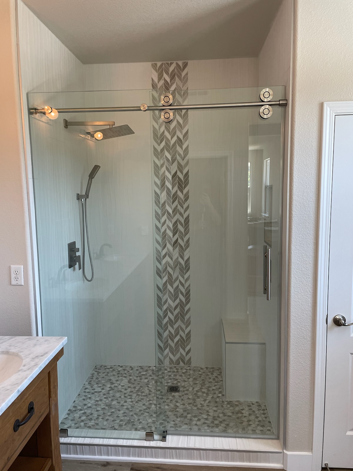 A bathroom with a walk in shower with a sliding glass door.