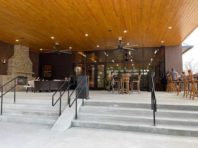 Outdoor patio with concrete steps, ramp, and seating under a wood-paneled ceiling.