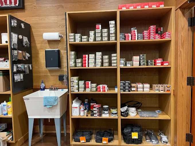 Wooden shelves stocked with various boxes and containers, sink, and dispensers in a room with wood paneling.