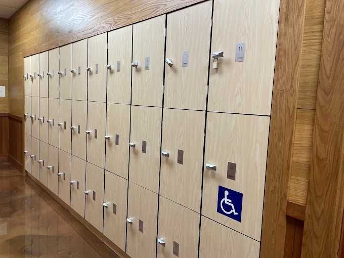 Row of beige lockers in a hallway, one marked with a blue wheelchair symbol for accessibility.