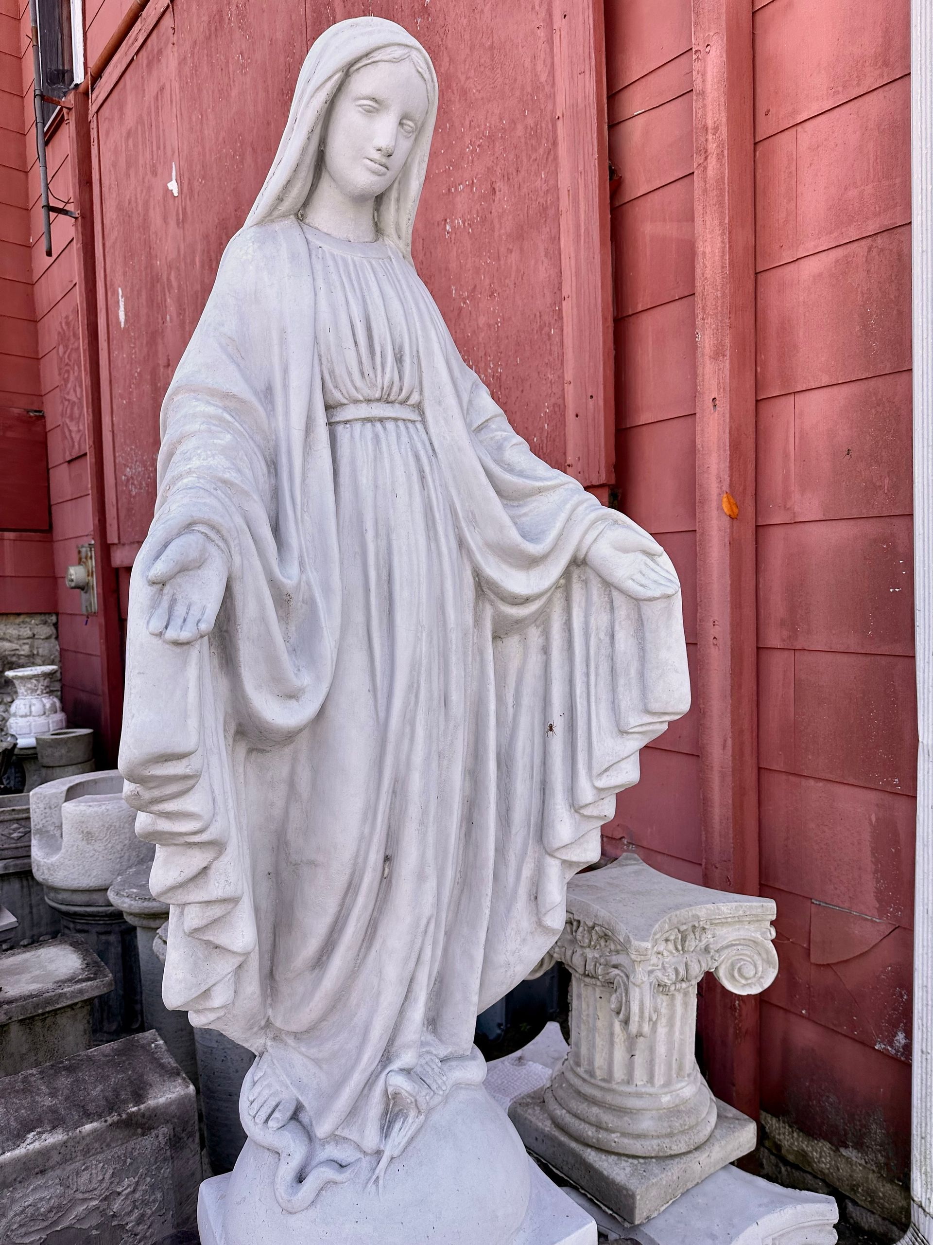 A statue of a woman standing in front of a red wall