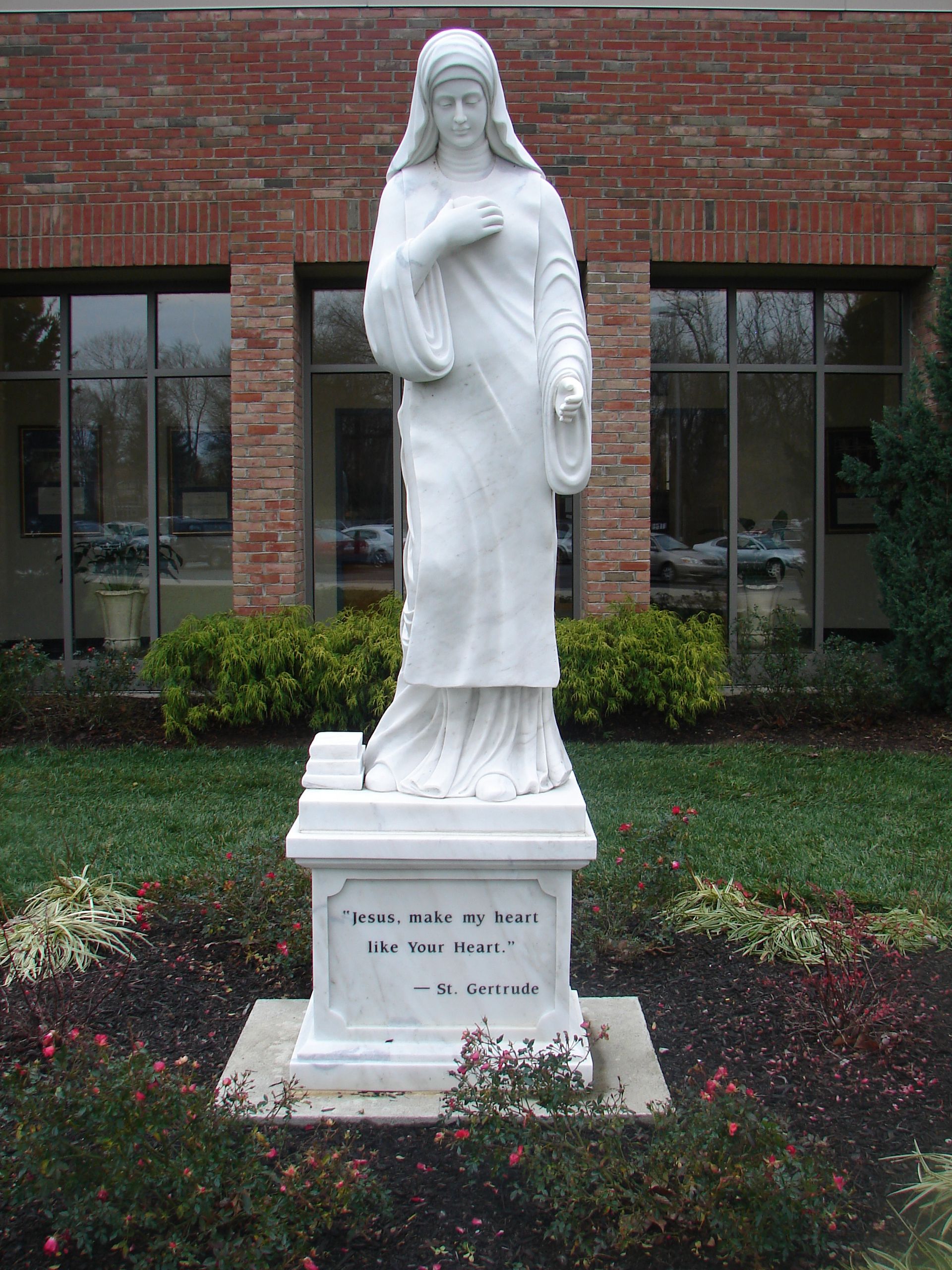 A statue of a woman standing in front of a brick building