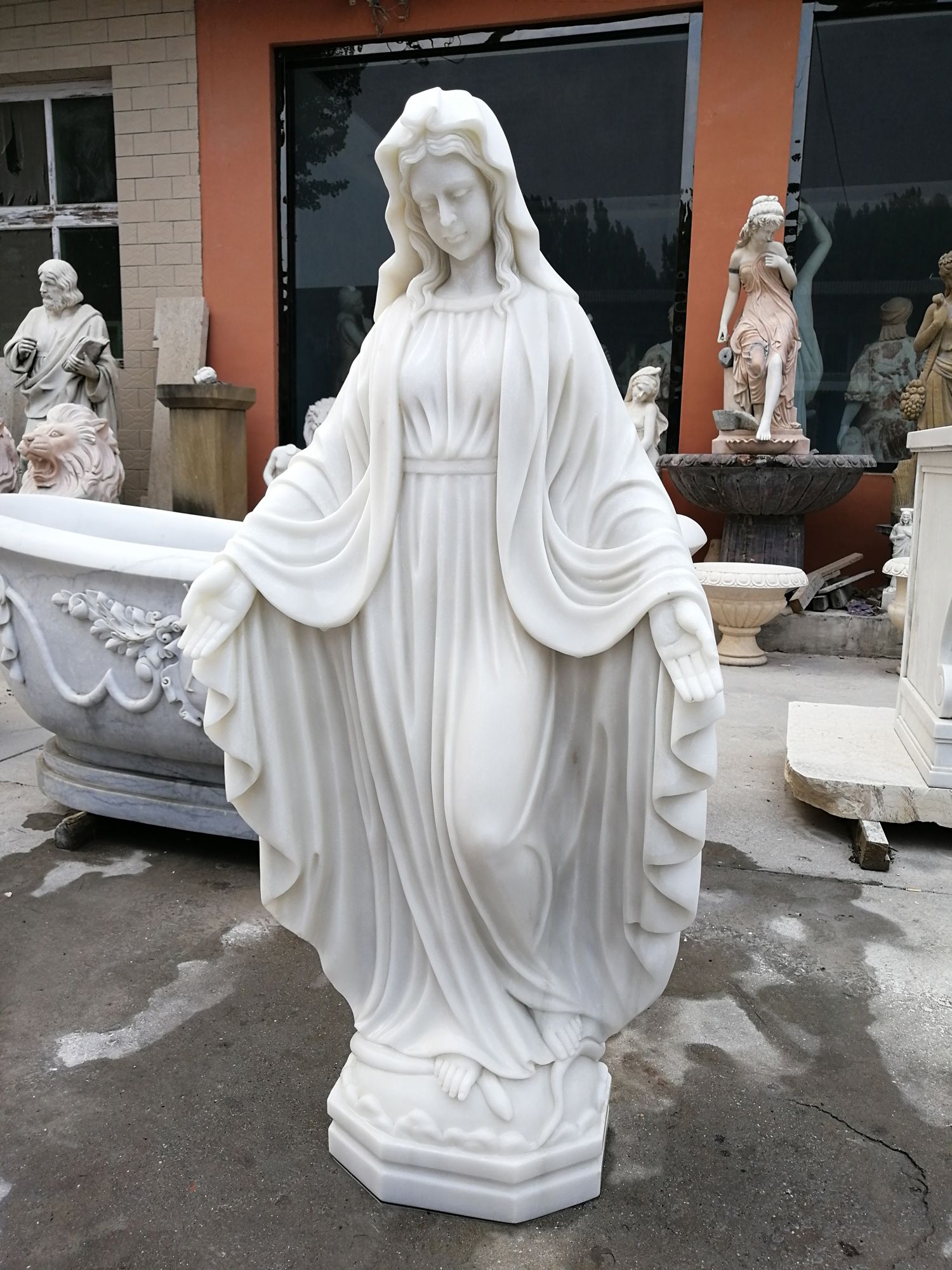 A white statue of a woman standing in front of a building