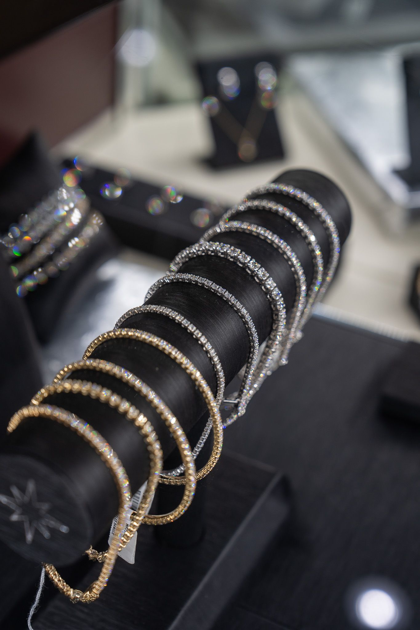 Gold and silver bangles stacked on a black display stand in a jewelry store