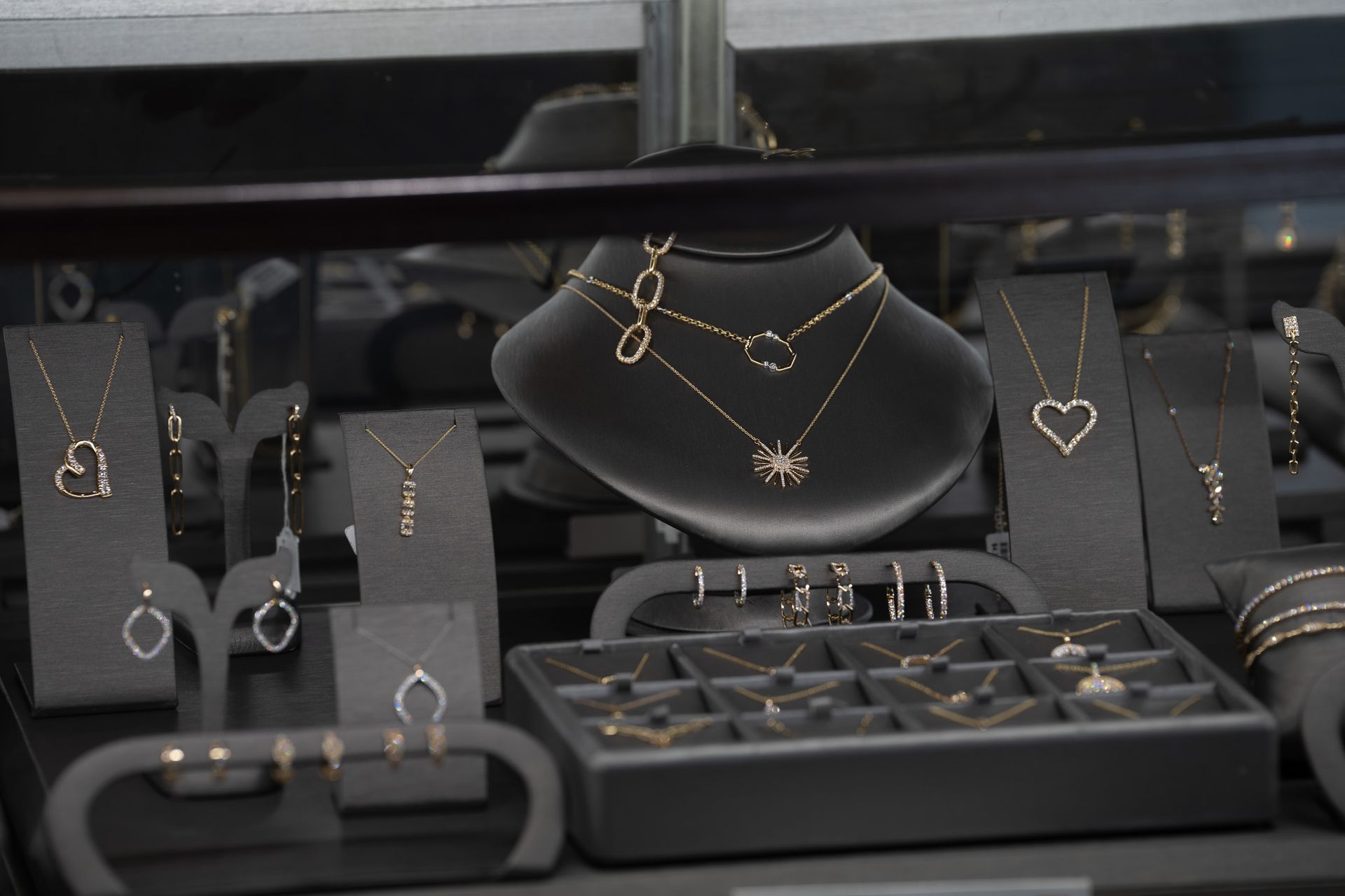 Jewelry display with silver and gold necklaces, bracelets, and rings on black stands and trays