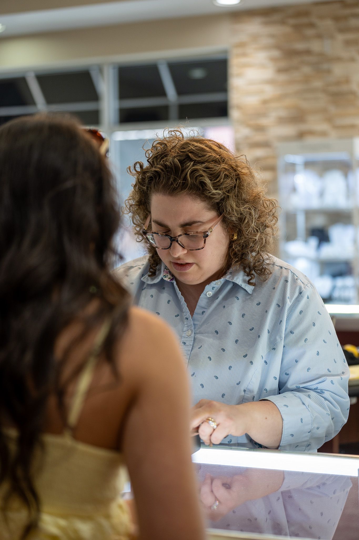 Person behind a counter handing an item to a customer in a bright shop