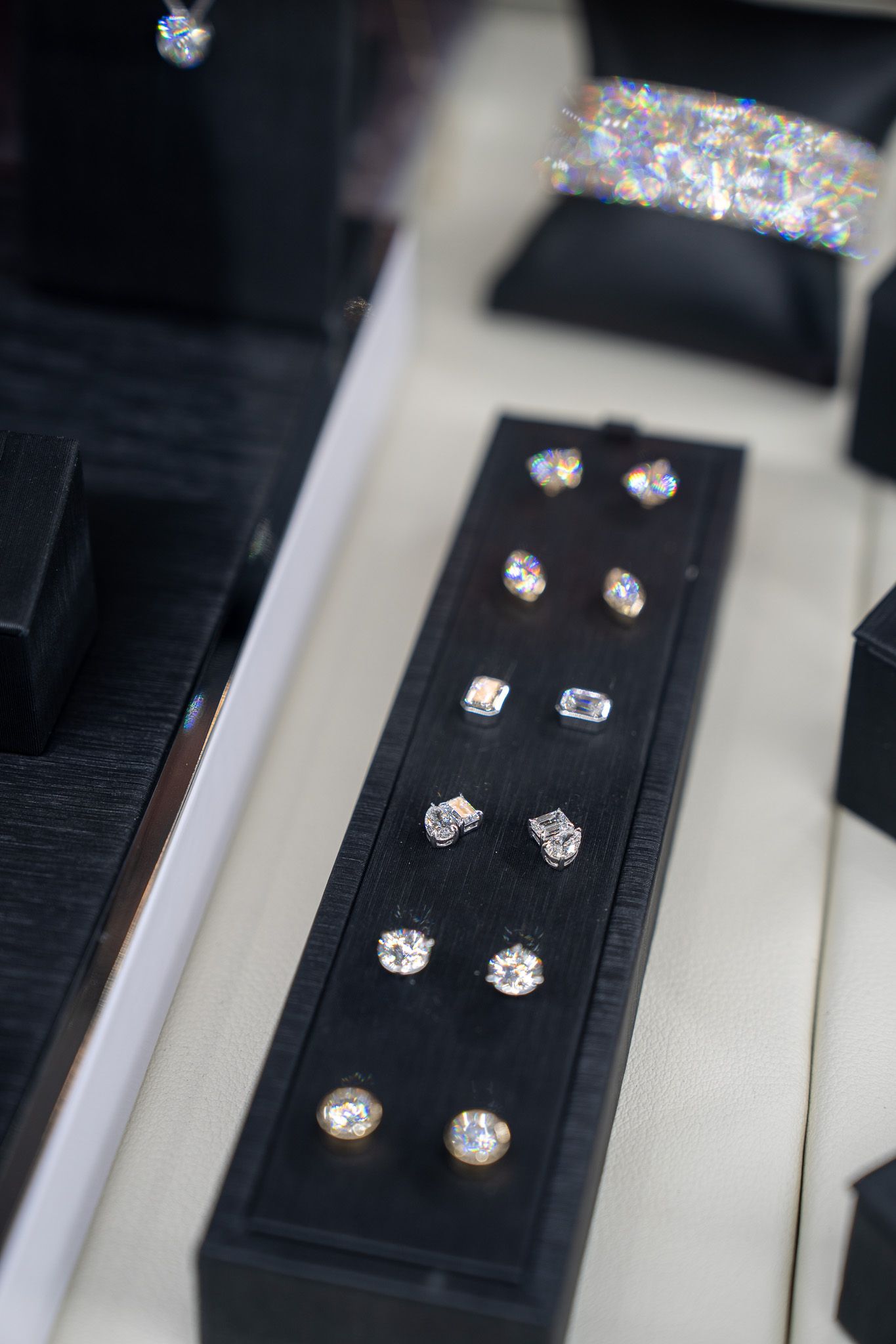 Diamond studs displayed on a black velvet jewelry tray in a display case