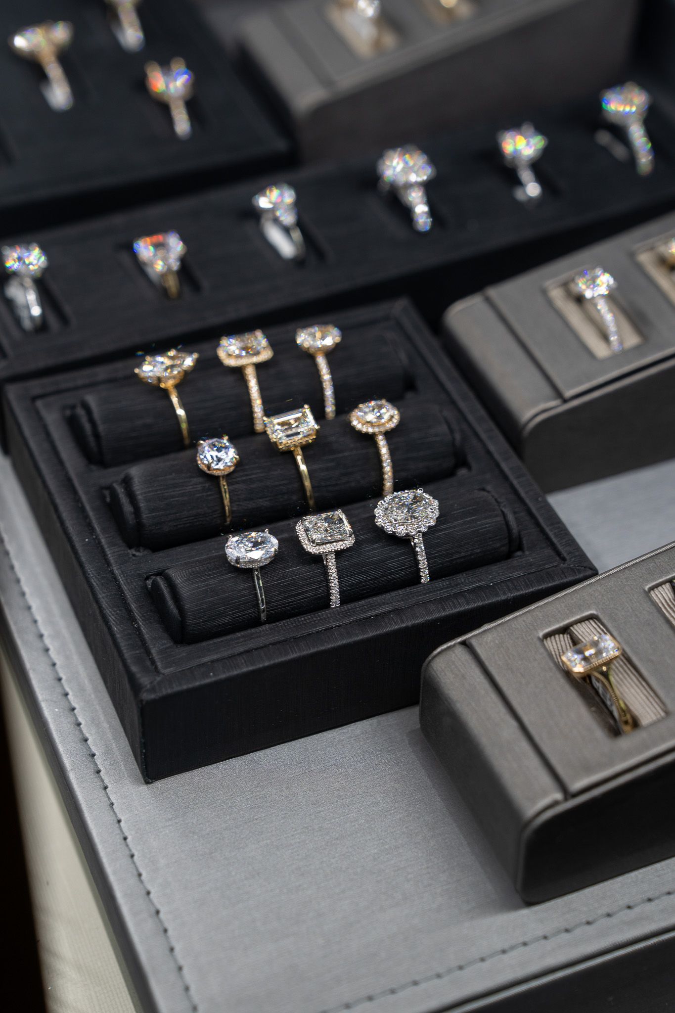 Jewelry display cases with assorted diamond rings on black velvet trays