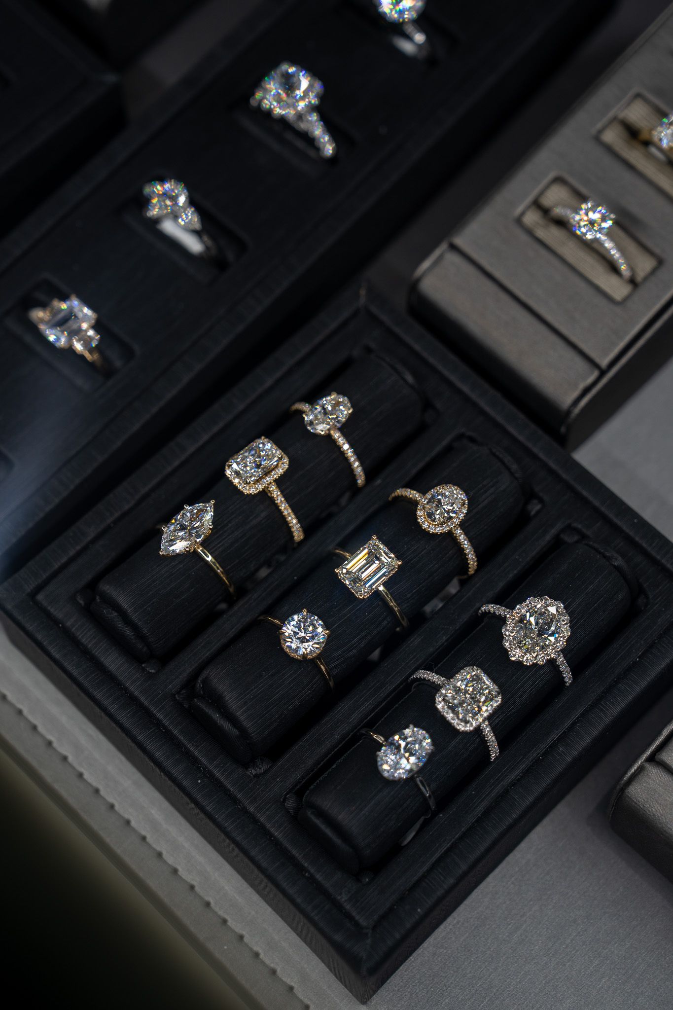 Black jewelry display case with several diamond rings on velvet trays