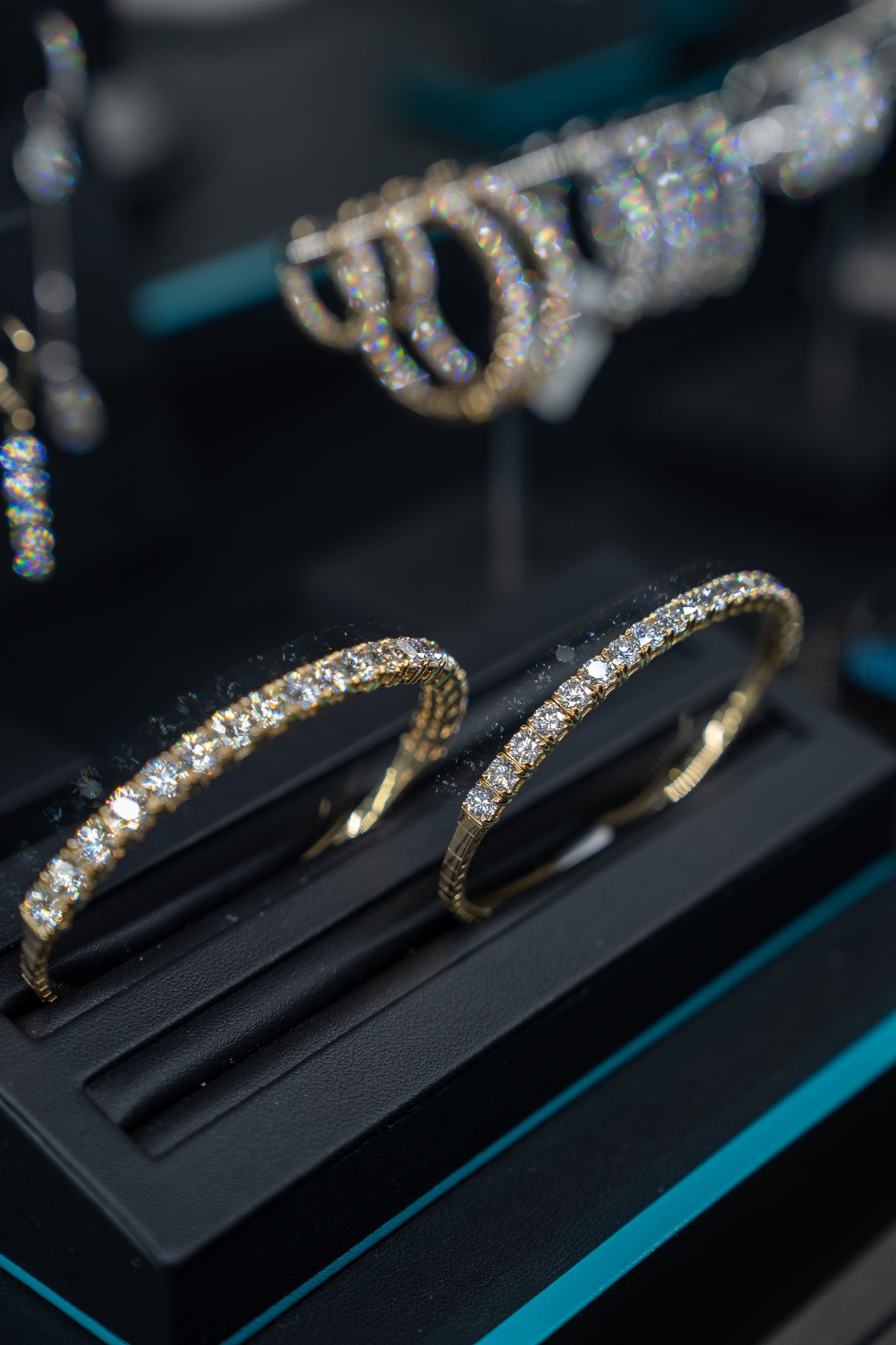 Two diamond-studded bracelets displayed on a black jewelry stand