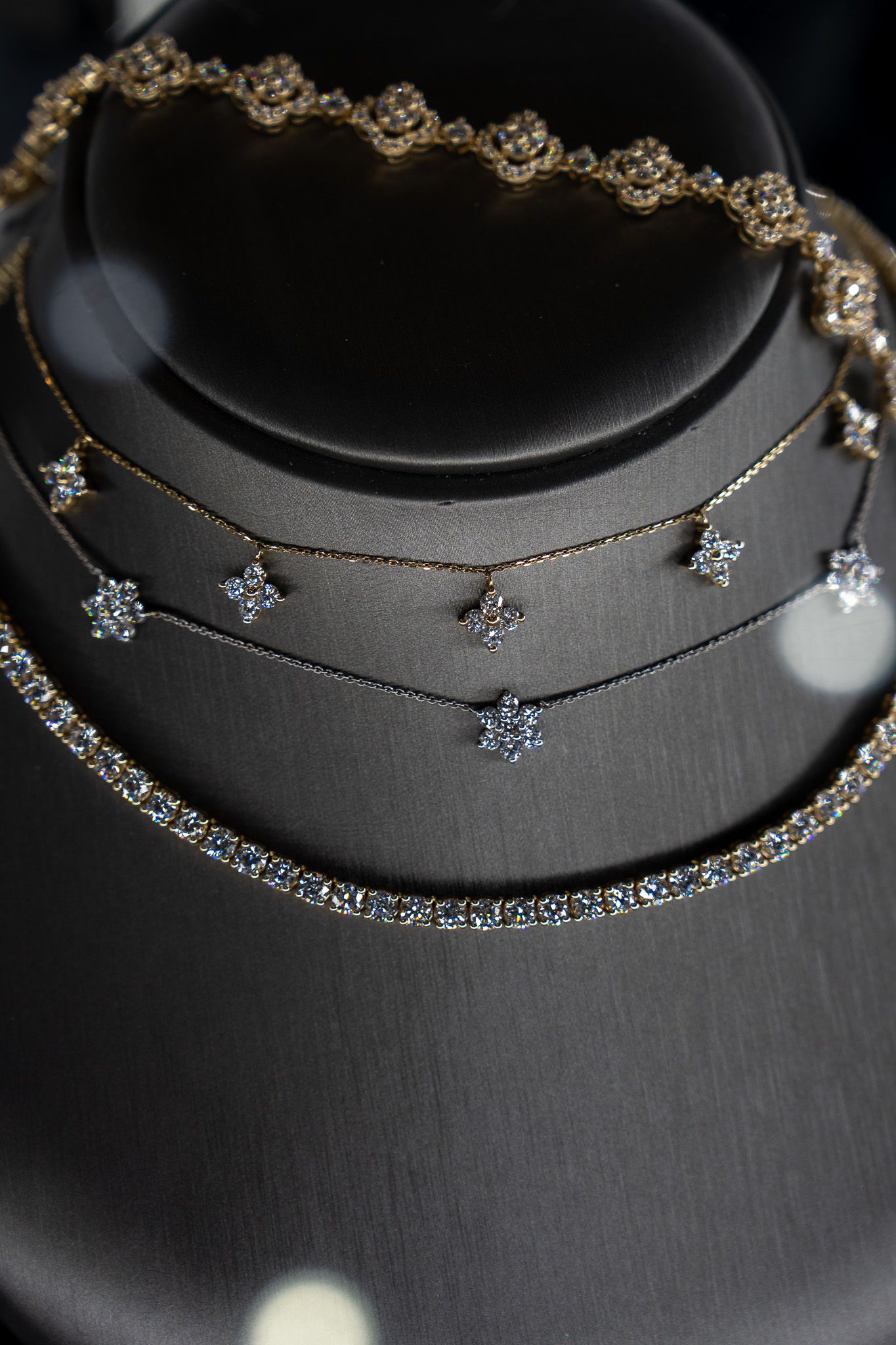 Layered gold and silver necklaces displayed on a black velvet bust