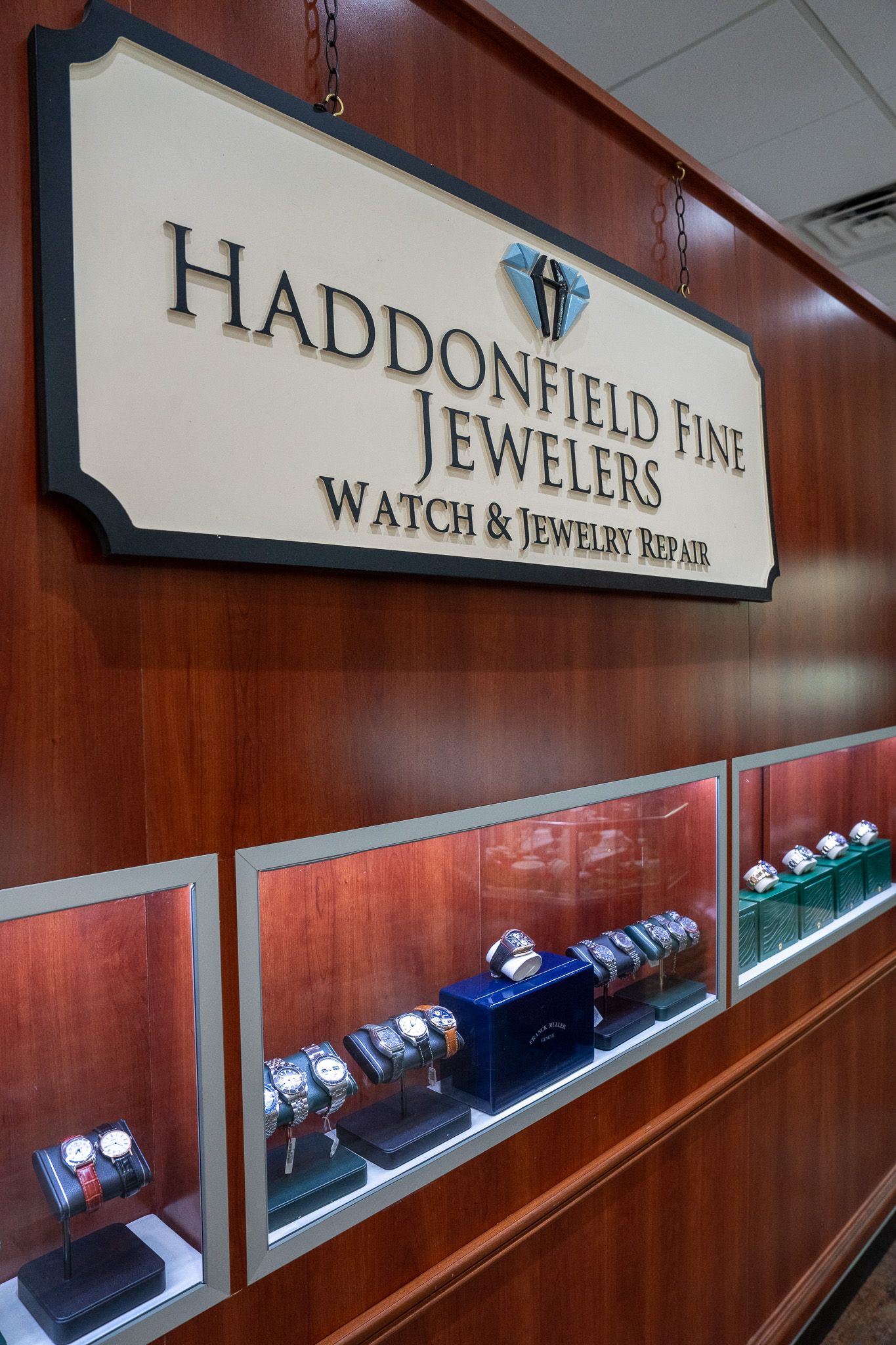 Store display case with handcrafted fine jewelry under a wood-paneled sign.