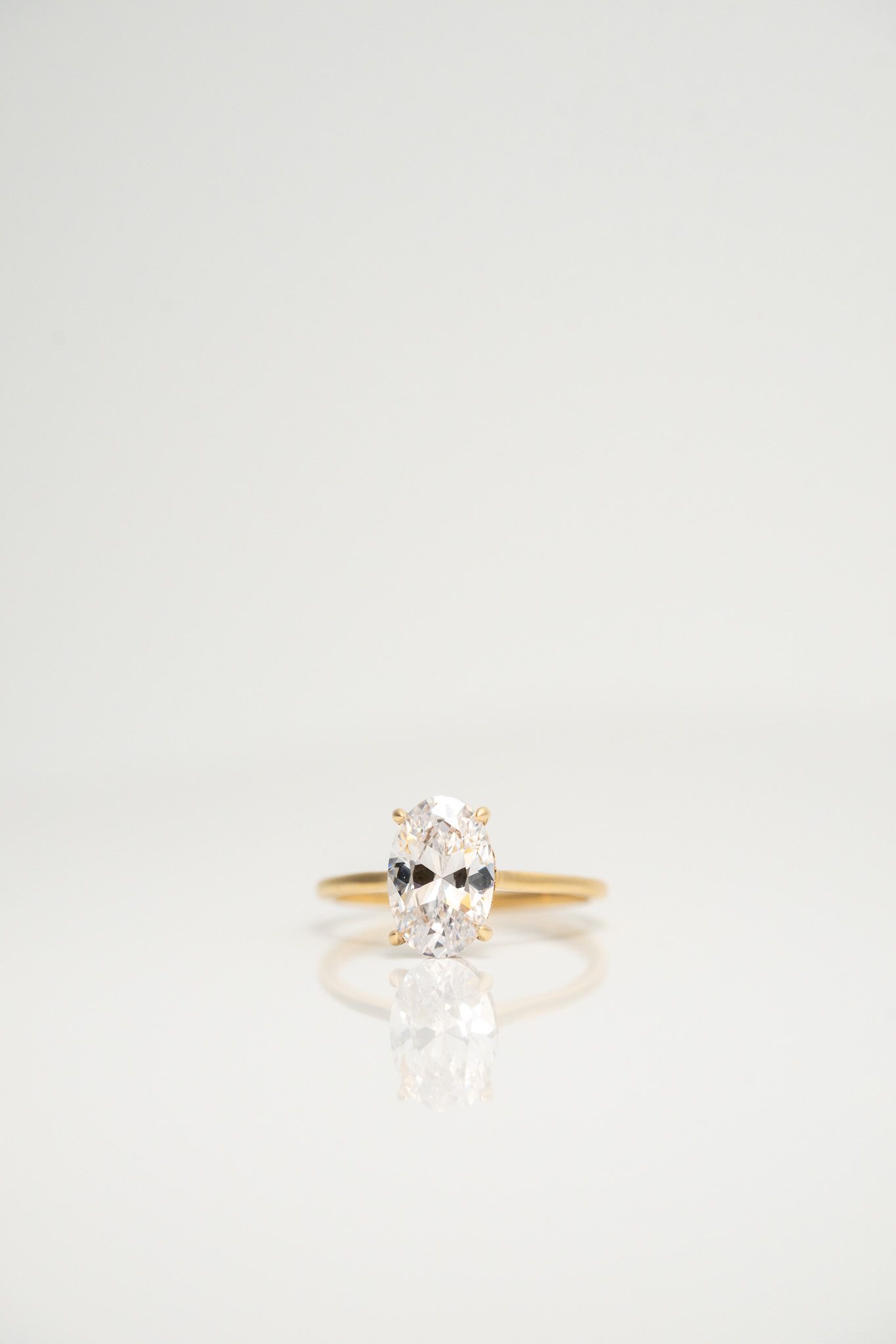 Gold ring with a clear round gemstone on a white background
