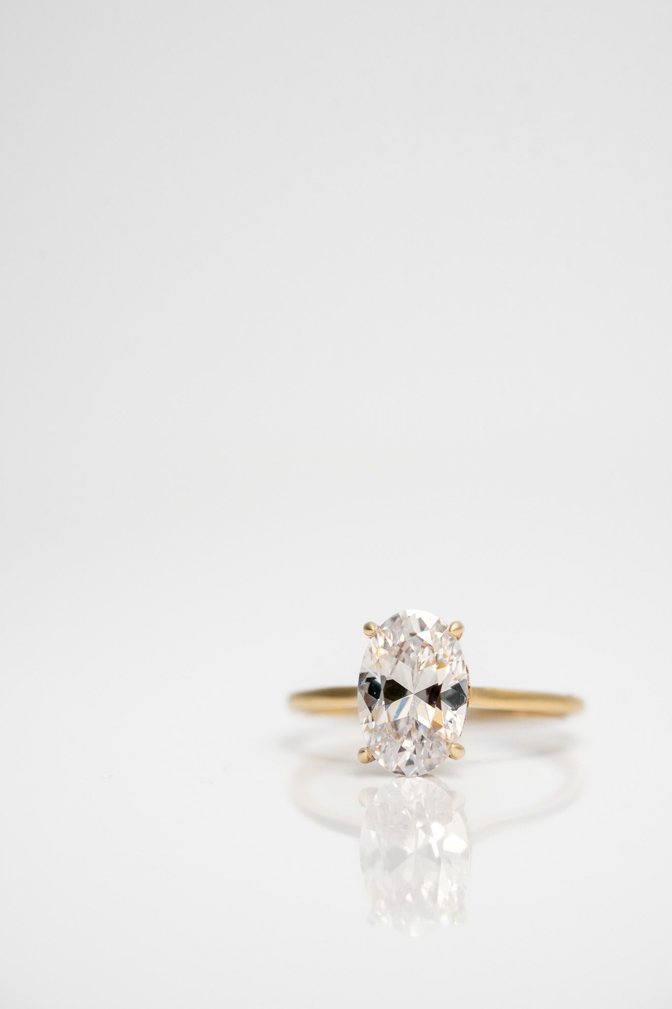 Gold ring with an oval clear gemstone on a white background