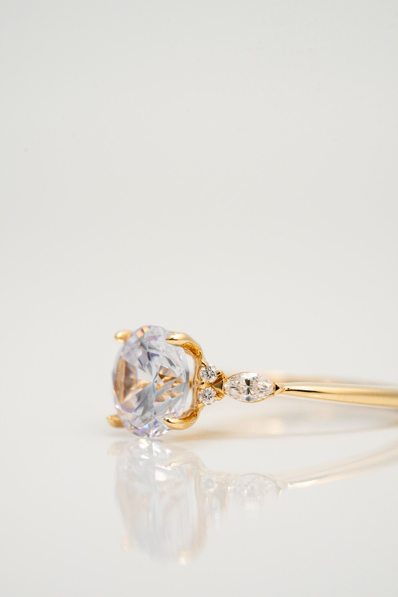 Gold ring with a clear gemstone on a white surface, shown in close-up.