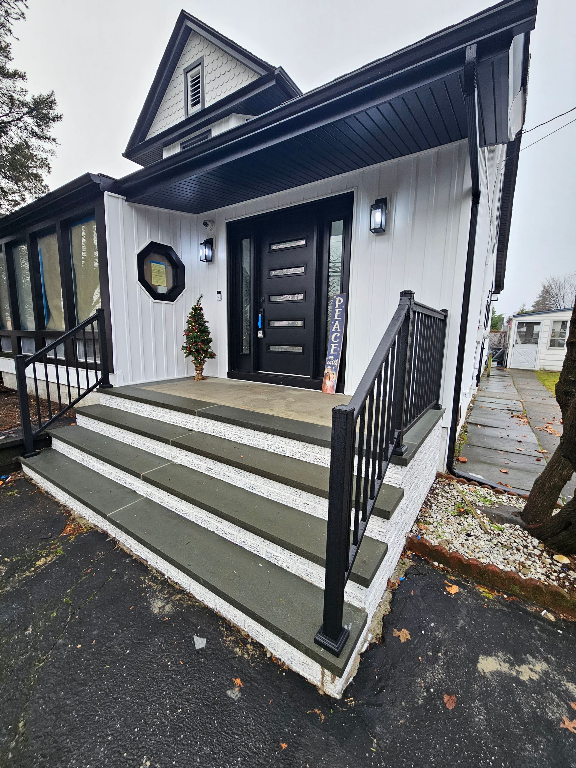 White house with black trim and door. Steps lead up to the entrance with a black railing.