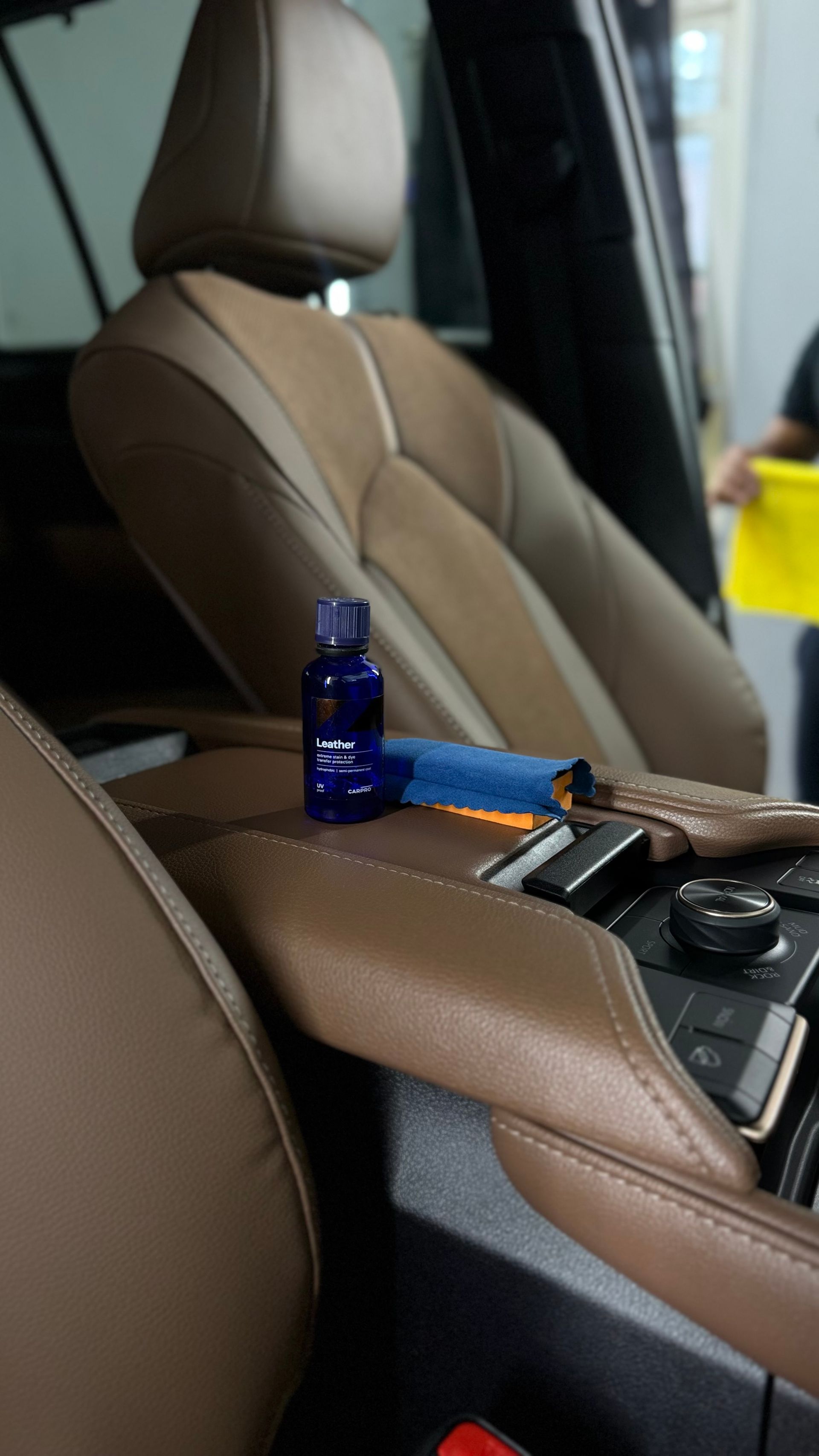 Brown car seat with a blue bottle, orange comb, and keys on the center console