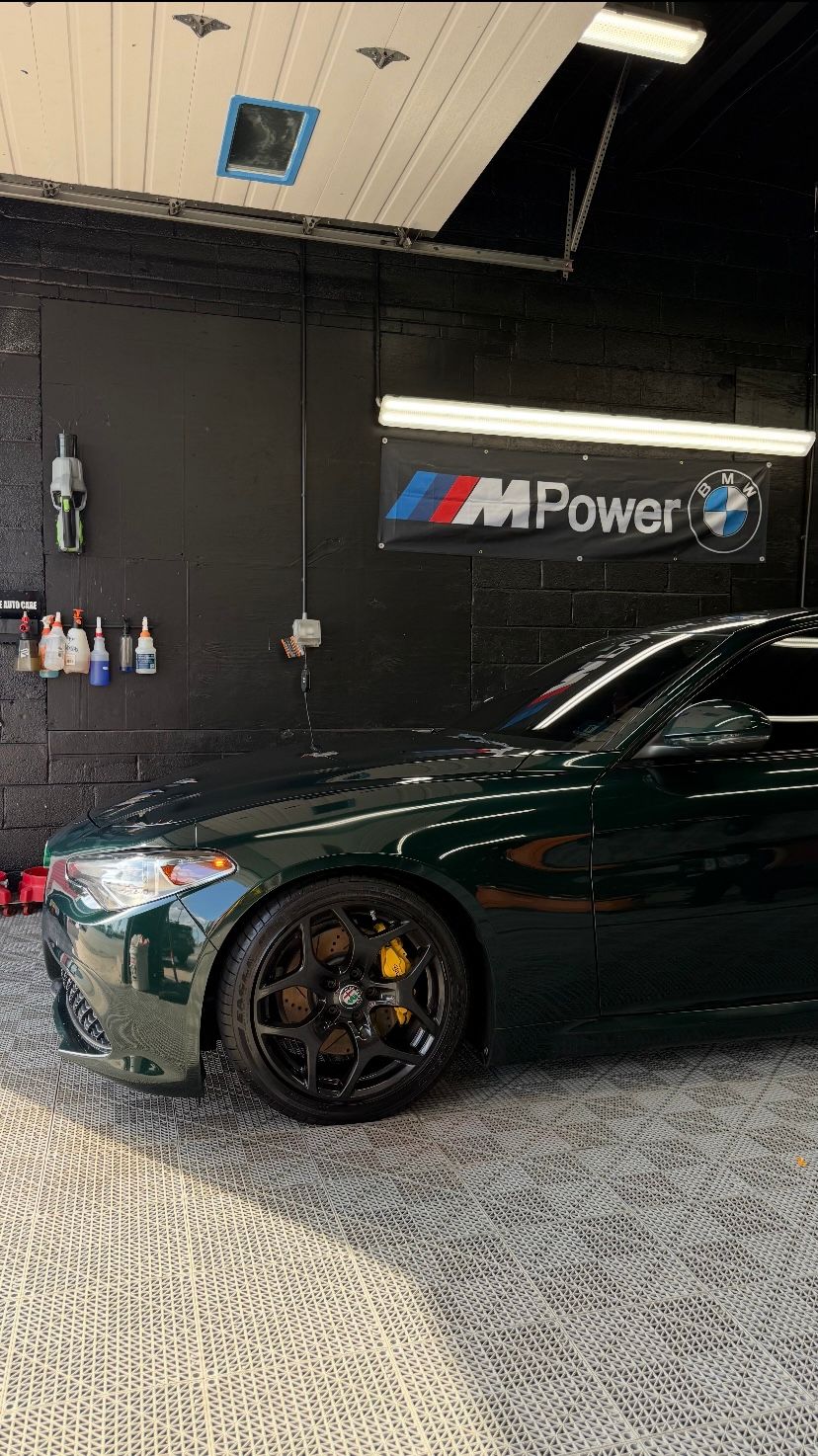 Black BMW sports car in a garage, parked in front of an M Power sign.