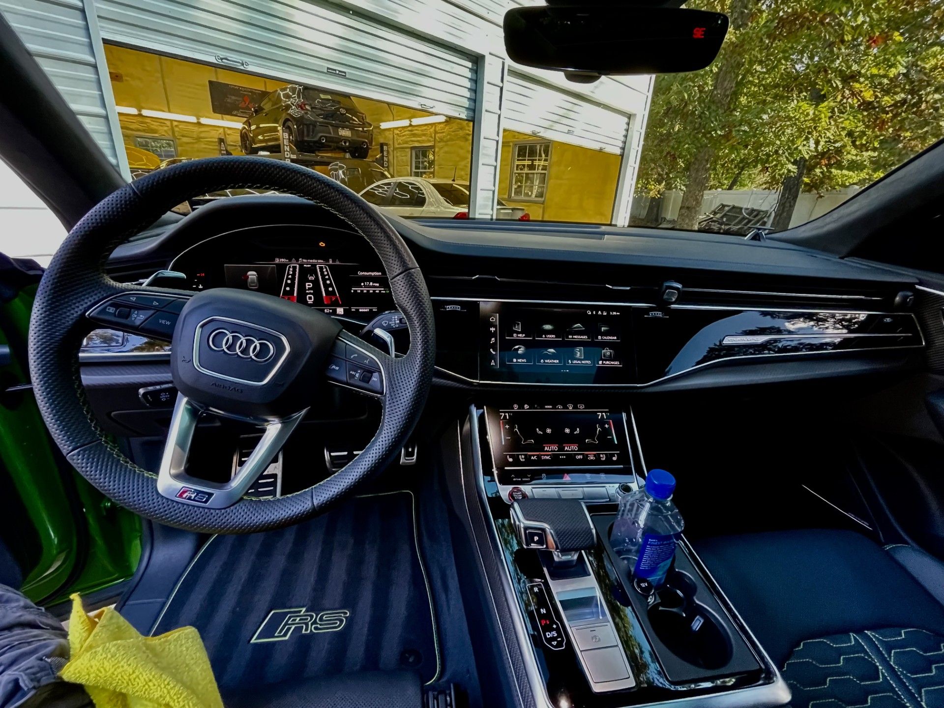 Sporty car interior with black leather steering wheel, digital dashboard, and center console, viewed from the driver's seat
