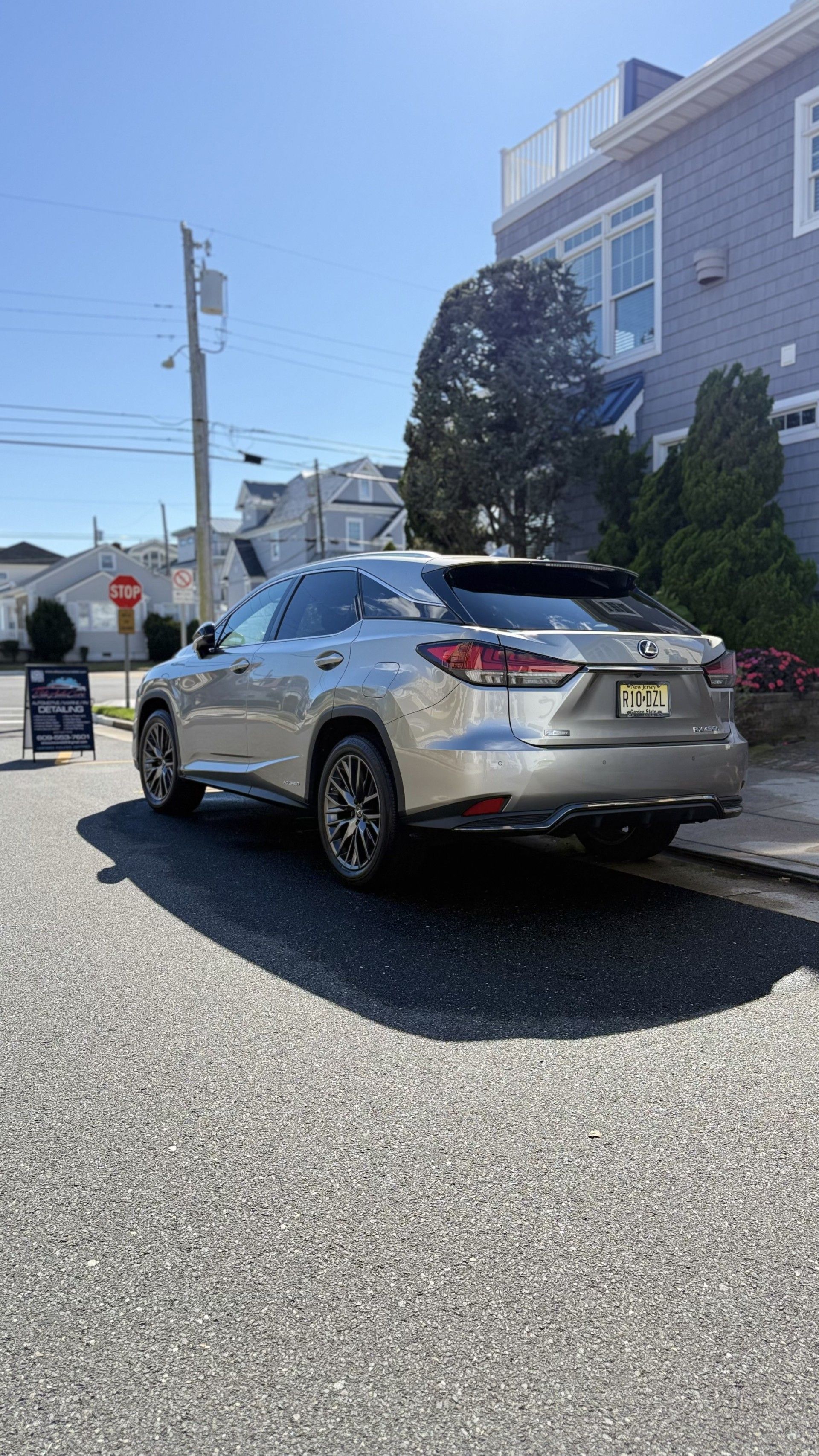 Silver SUV parked on a sunny residential street beside a house and utility poles.