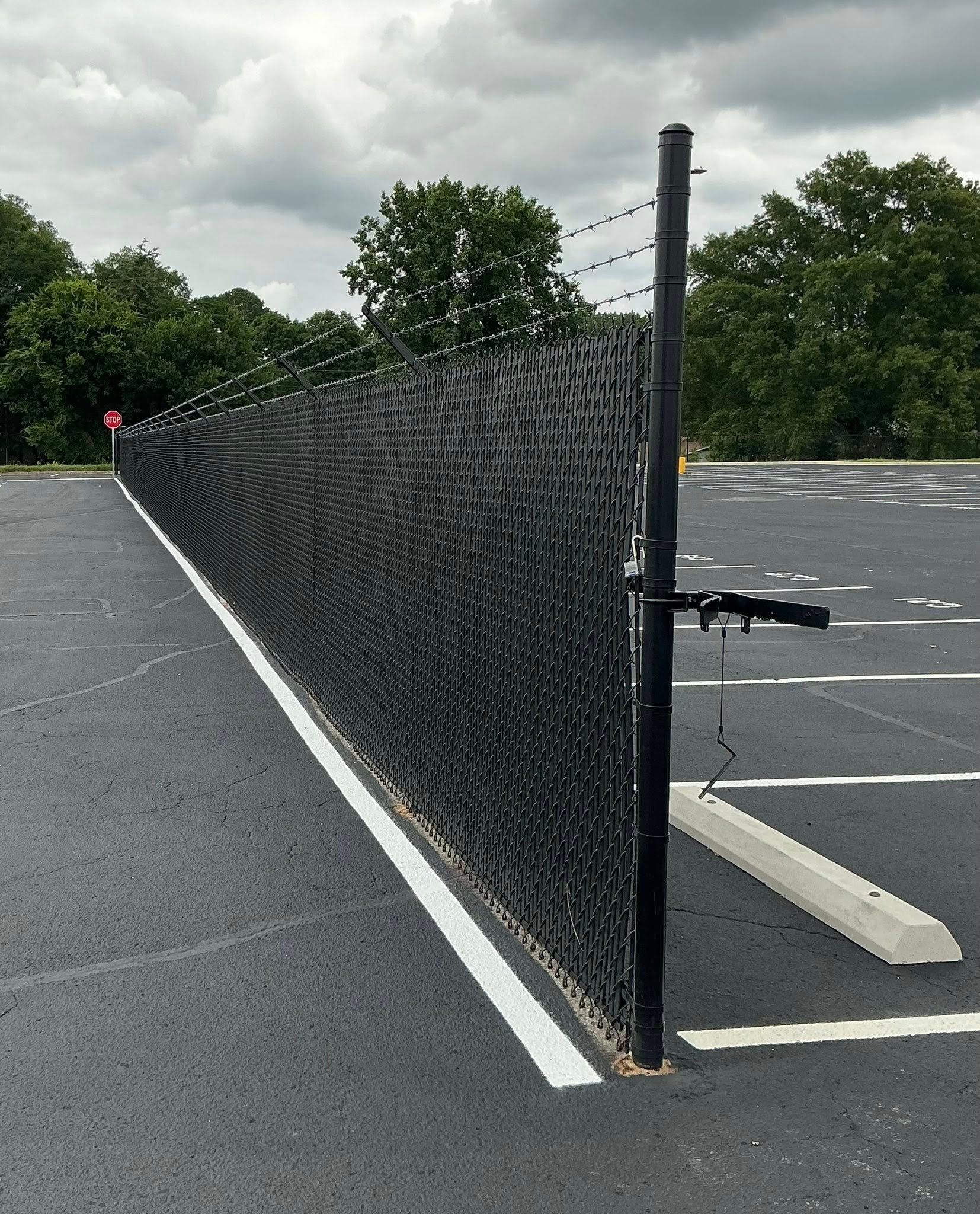 Black mesh barrier on a post beside an empty parking lot under cloudy skies