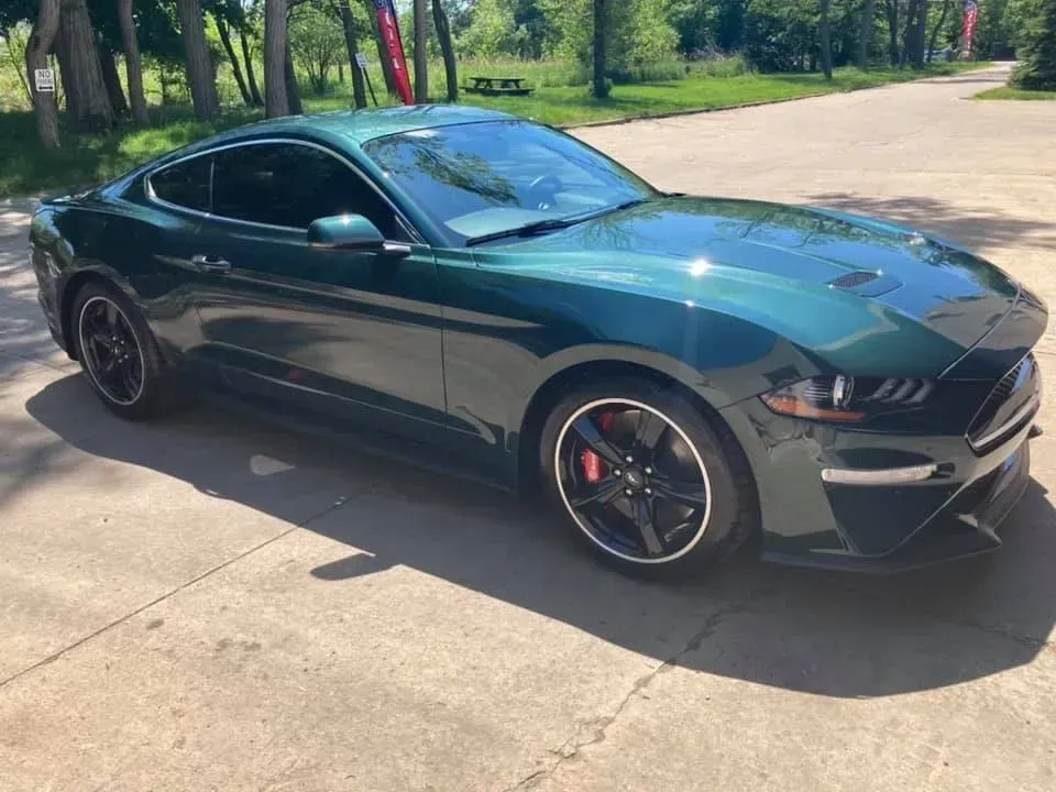 Green Ford Mustang sports car parked on a concrete surface.