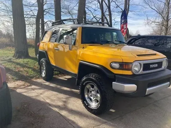 Yellow Toyota FJ Cruiser SUV parked outdoors with roof rack.