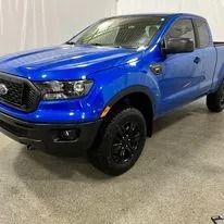 Blue Ford Ranger truck with black wheels.