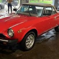 Red convertible car with a tan roof.