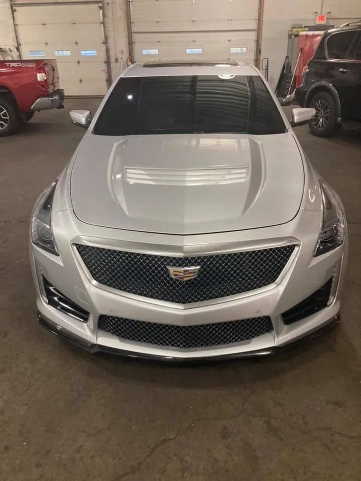 Silver Cadillac sedan parked in a garage with closed overhead doors.