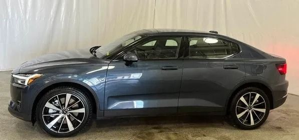 Dark gray Polestar 2 electric car parked indoors. Side view showing wheels, doors, and lights.