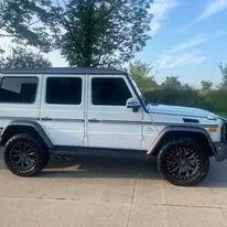 White SUV with black wheels parked outside.