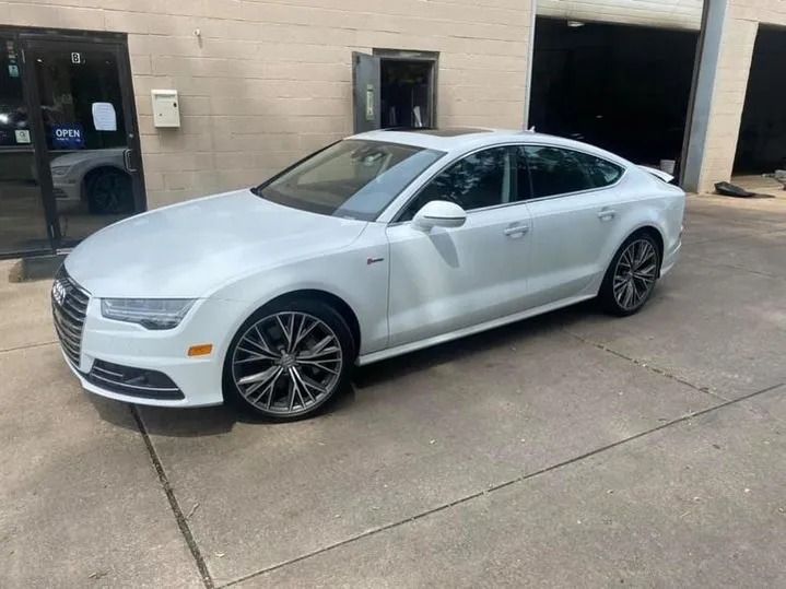 White Audi A7 parked outside a building with a black door and garage.