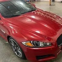Red Jaguar car with black roof, parked inside a building.