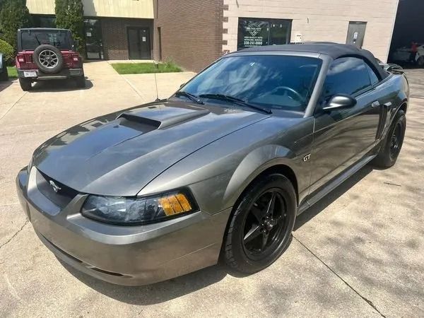 Gray convertible Ford Mustang with black wheels parked outside.