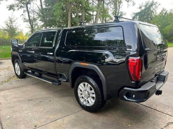 Black GMC pickup truck with a camper shell parked on a concrete surface.