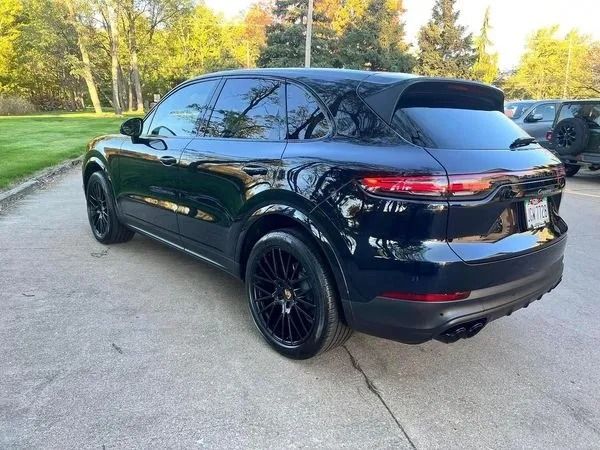 Black Porsche Cayenne SUV with black wheels on a paved driveway.