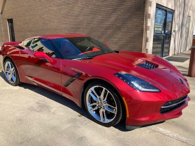 Red Corvette sports car parked in front of a building with shiny chrome wheels.