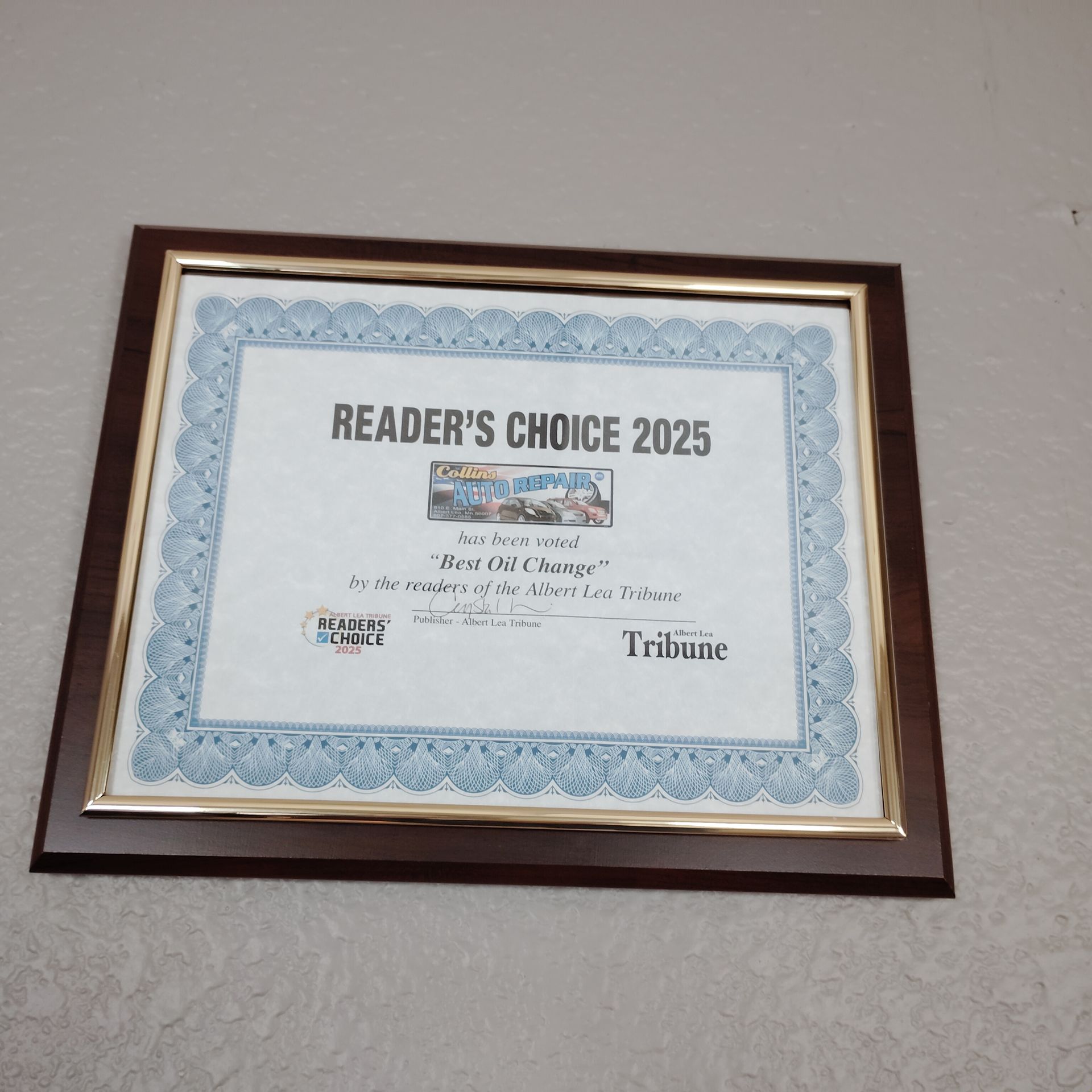 Framed Reader’s Choice 2025 award certificate on a wall with a blue border and wood frame