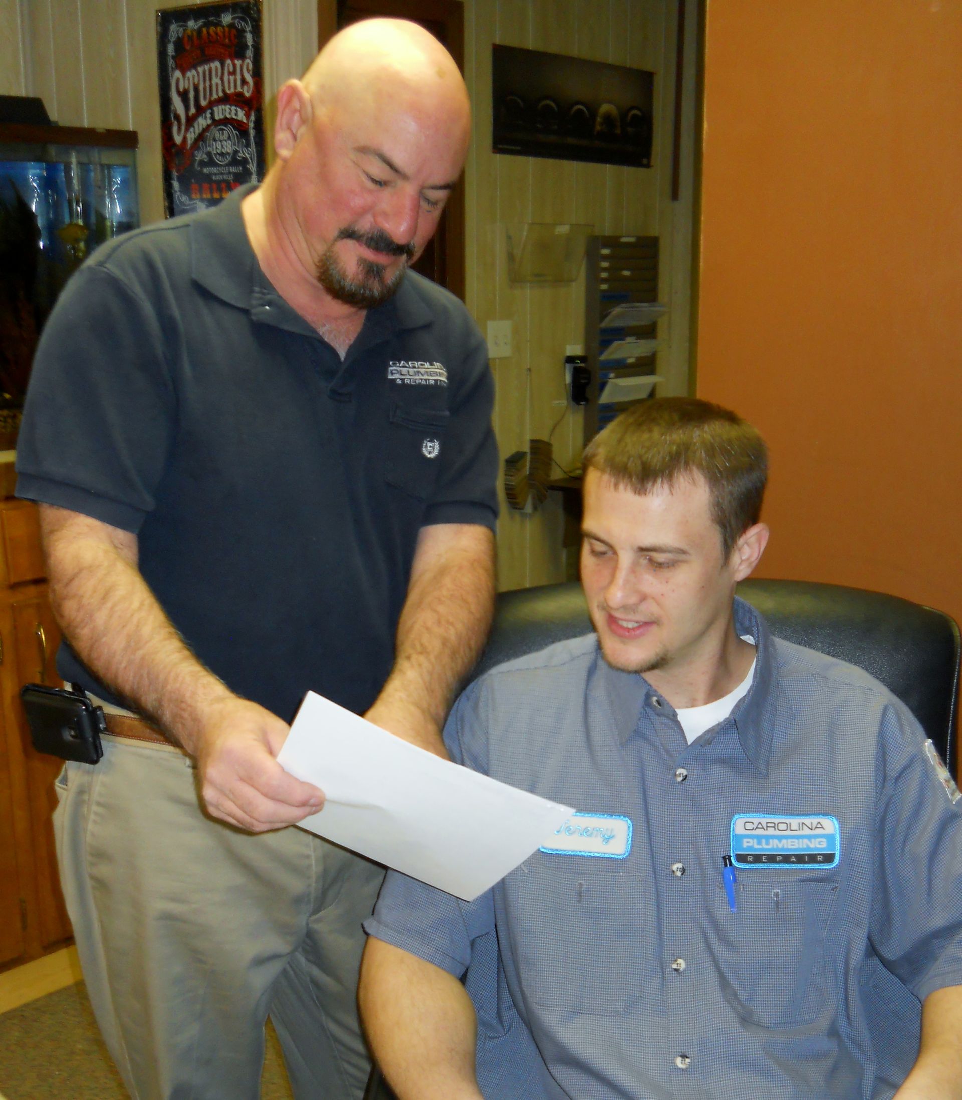 A man holding a piece of paper next to a man in a chair