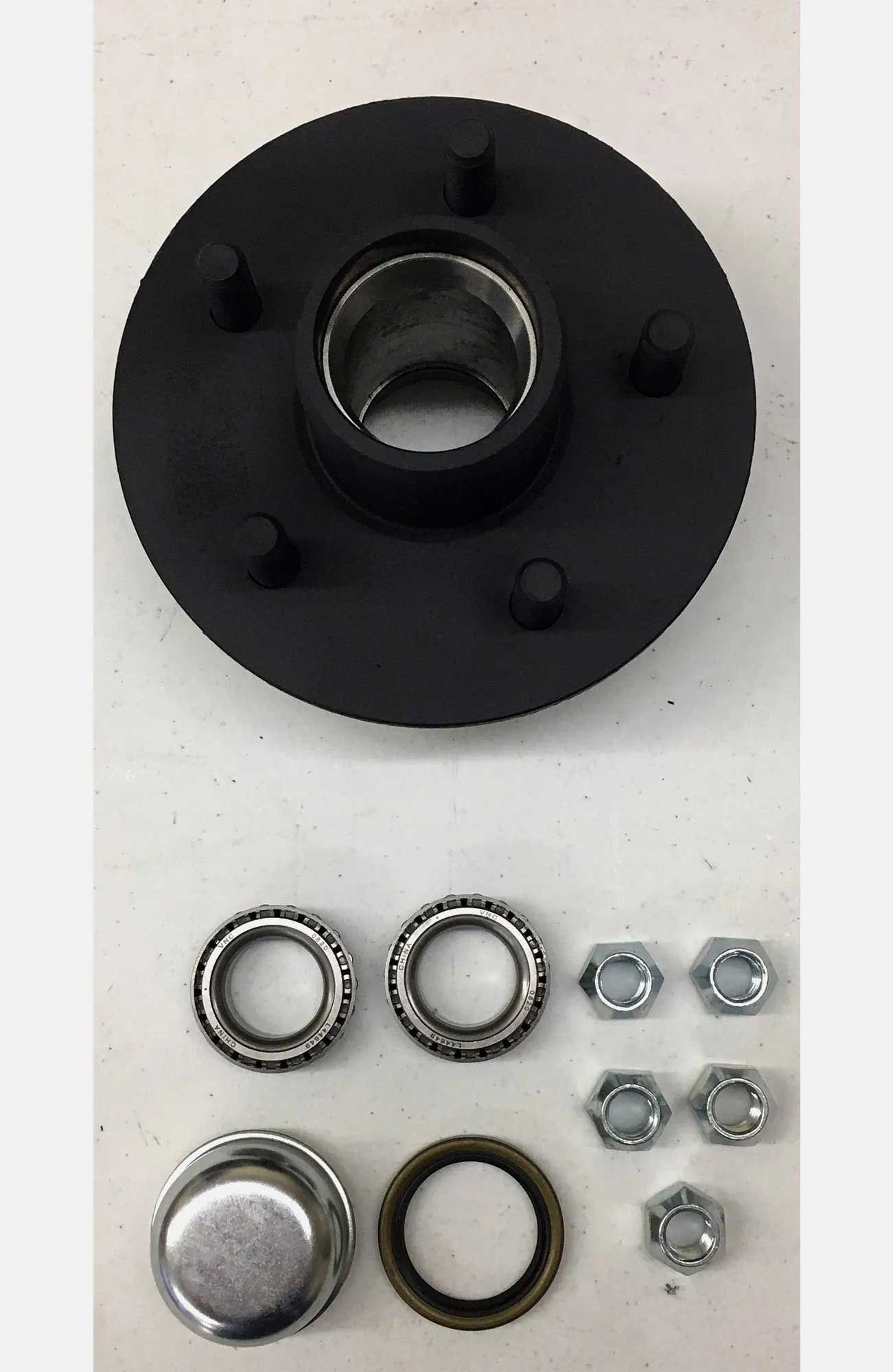 Black trailer hub assembly with bearings, nuts, and a grease cap arranged on a white surface.