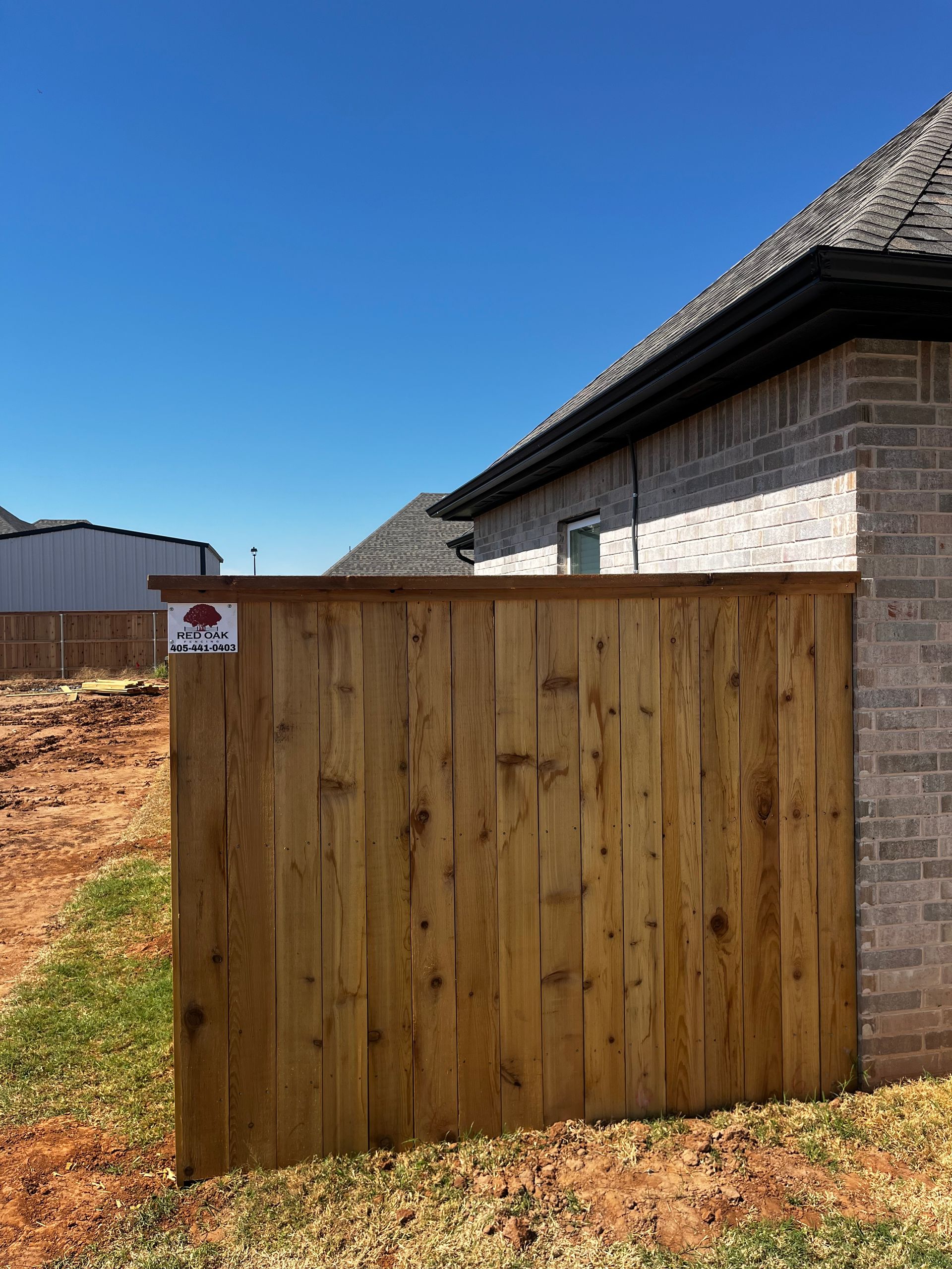 Wooden fence next to a brick house.