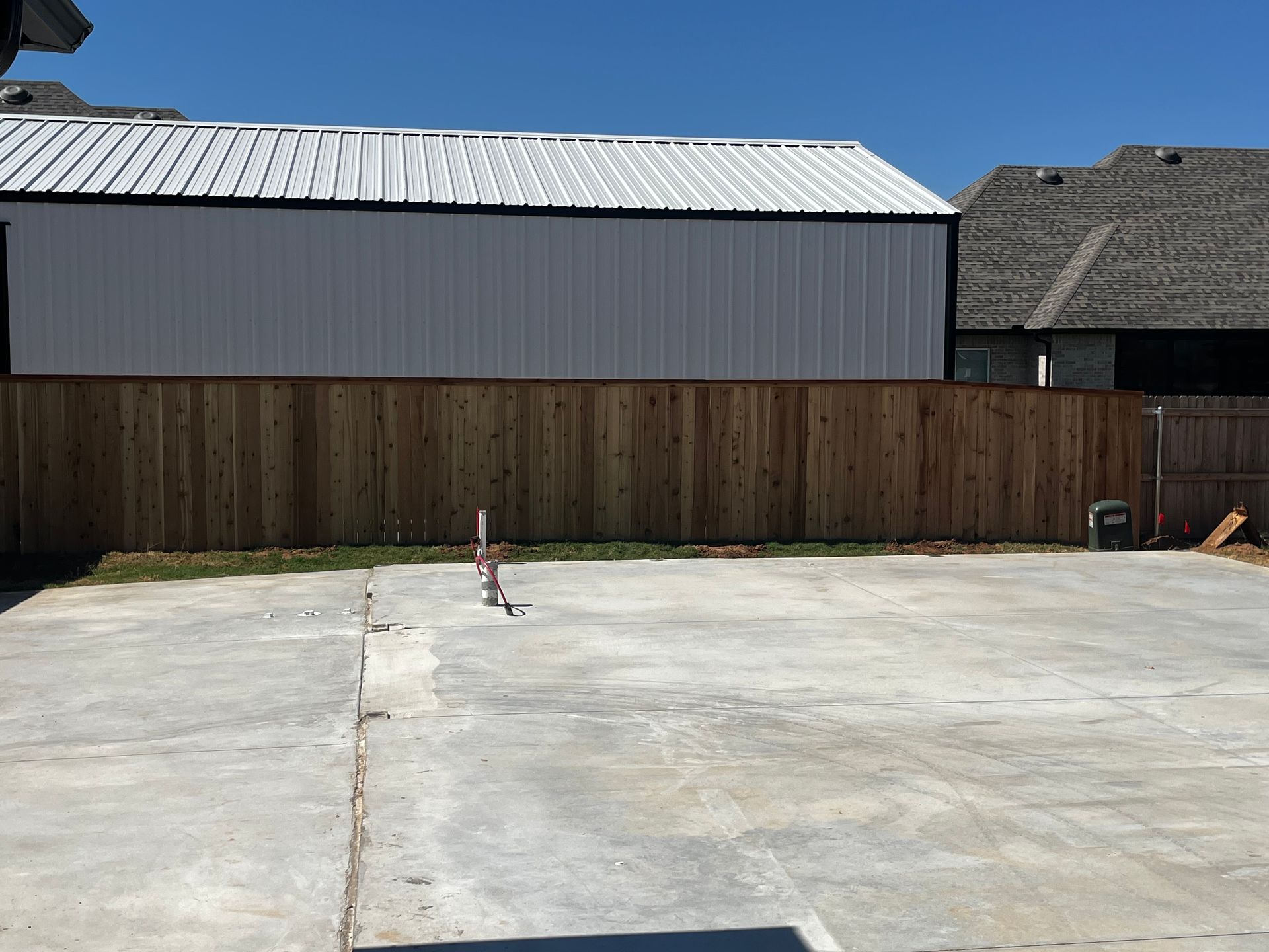 A concrete backyard with a wooden fence.