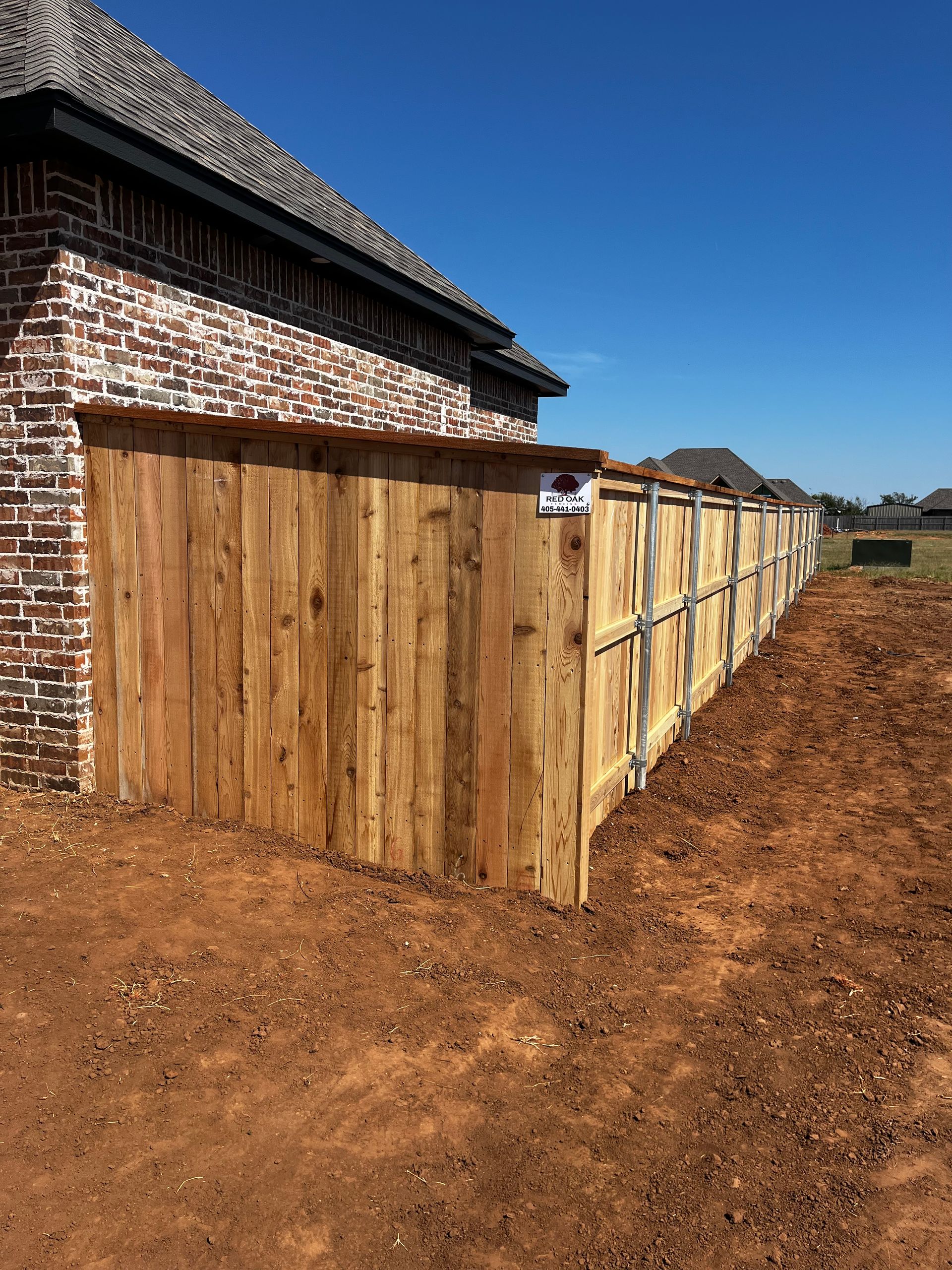 Wooden fence extending from a brick building on a sunny day.