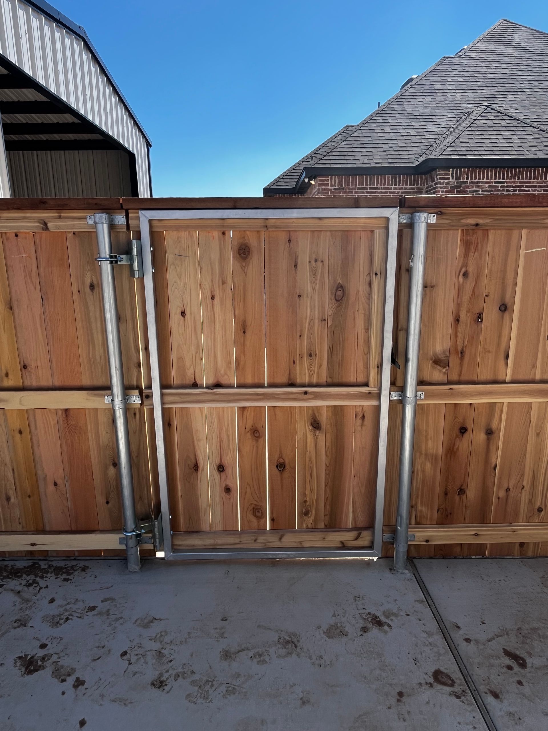 Wooden gate in a wooden fence, with metal frame.